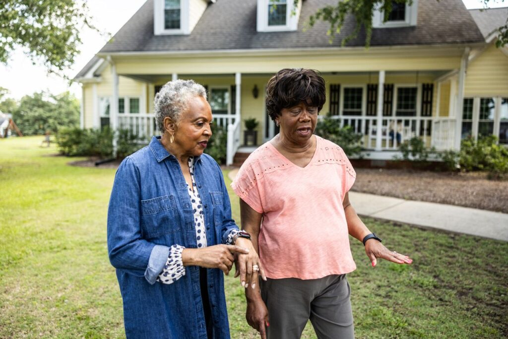 Senior women walking and talking in front of rural farm home