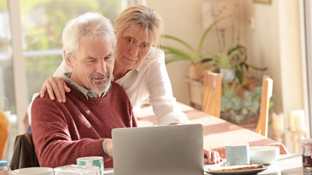 couple at kitchen breakfast bar looking at laptop
