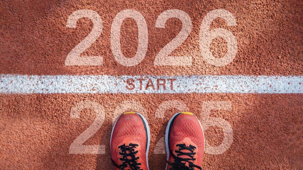 New year 2026 concept, beginning of success. Text 2026 written on asphalt road and male runner preparing for the new year. Concept of challenge or career path and change.