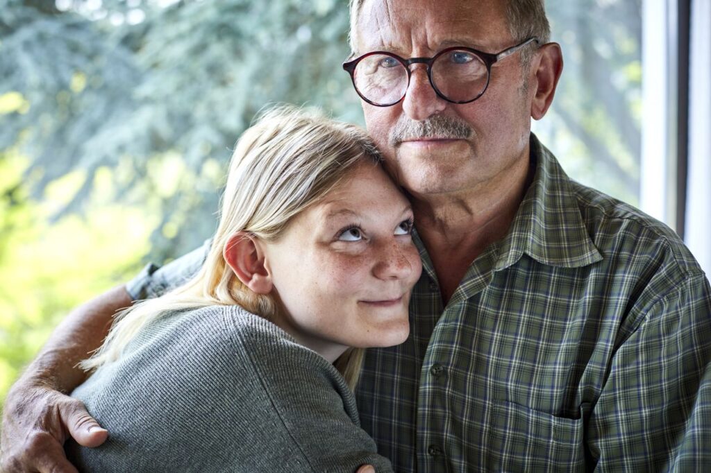 Grandfather hugging adult granddaughter at the window