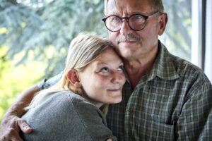 Grandfather hugging adult granddaughter at the window