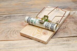 Dollars in a mousetrap with a hundred dollar bill on a wooden background with a copy space